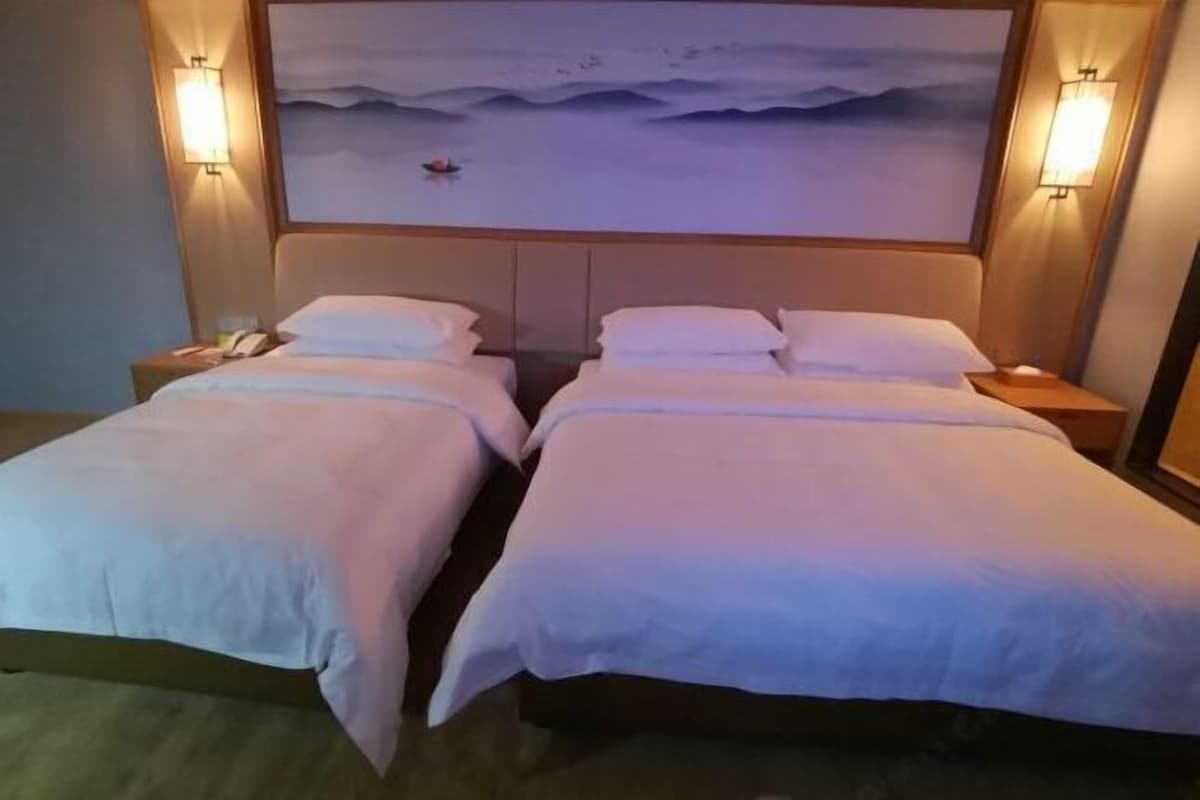A double room with two beds, nightstands, and wall-mounted lamps.