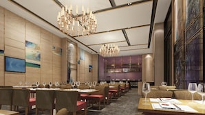 Ein modernes Restaurant-Interieur mit mehreren Esstischen und Stühlen, einer großen Kristallleuchter und Kunstwerken an den Wänden.