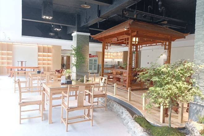 A modern interior with wooden furniture, a central column, and a small indoor garden.