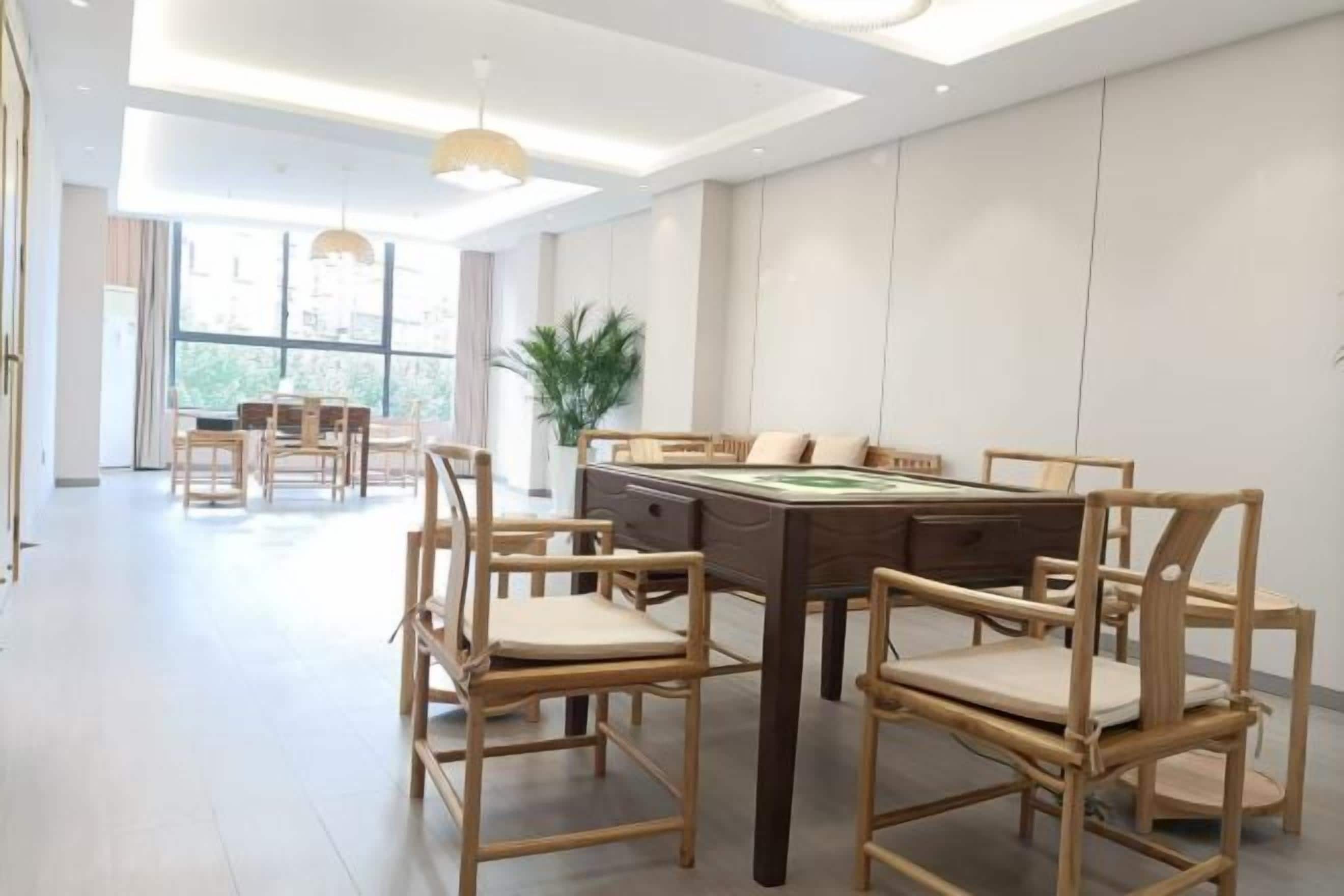 Un'area pranzo moderna con tavolo da biliardo, sedie in legno e una grande finestra che garantisce luce naturale.