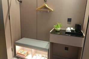 A compact hotel room with a built-in shelf containing slippers and a small potted plant. - Yangguang Express Hotel (Xiushan County)
