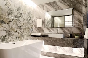 A modern bathroom with a freestanding bathtub, a large mirror, and marble walls. - Yangguang Express Hotel (Xiushan County)