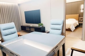 A hotel room with a bed, two armchairs, a TV, and a small table.