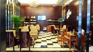 A lobby with a checkered floor, seating area with chairs and tables, a chandelier, and a television on the wall. - The BLD International Hotel (Yuncheng)