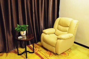 A beige leather armchair with a small side table and a potted plant.