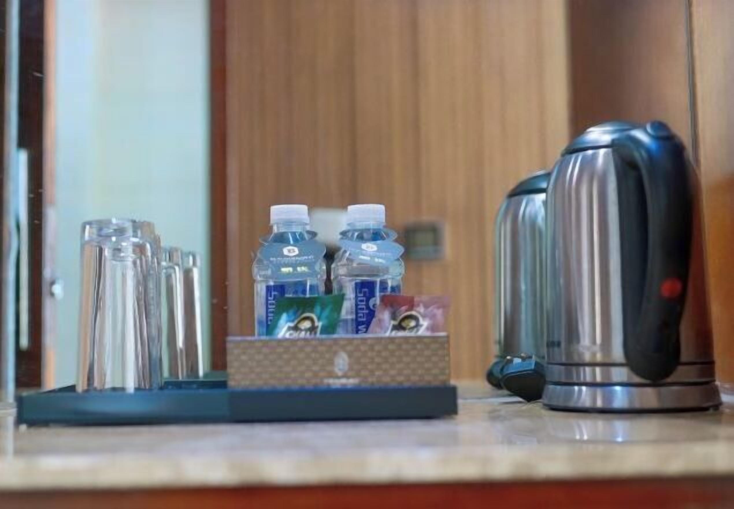 Una encimera de cocina con una tetera, un juego de vasos de vidrio y una caja de agua embotellada.