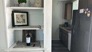 Una cuina amb armaris blancs, un refrigerador negre i un ventilador de sostre.