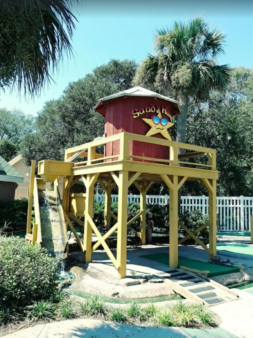 A wooden lifeguard tower with a starfish logo and the name 'Sandy Shores' on it.