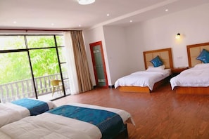 A hotel room with two beds, a balcony, and a view of greenery. - Guilin Guzhen Inn (Dawei Guzhen Inn) (Lingchuan)