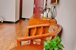 Una mesa de comedor de madera con sillas, una planta en maceta y una puerta roja al fondo.