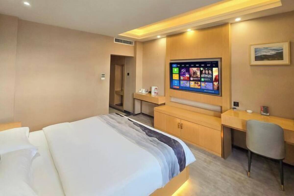 Hotellihuone, jossa on sänky, työpöytä, tuoli, televisio ja pieni kylpyhuone.