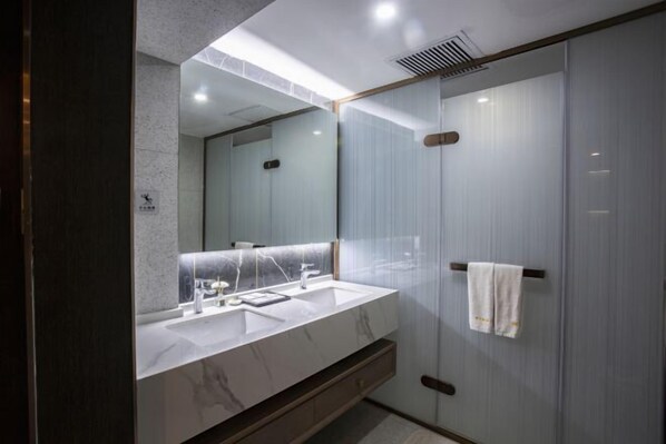 Un baño moderno con lavamanos de mármol, un espejo grande y cabina de ducha de vidrio.