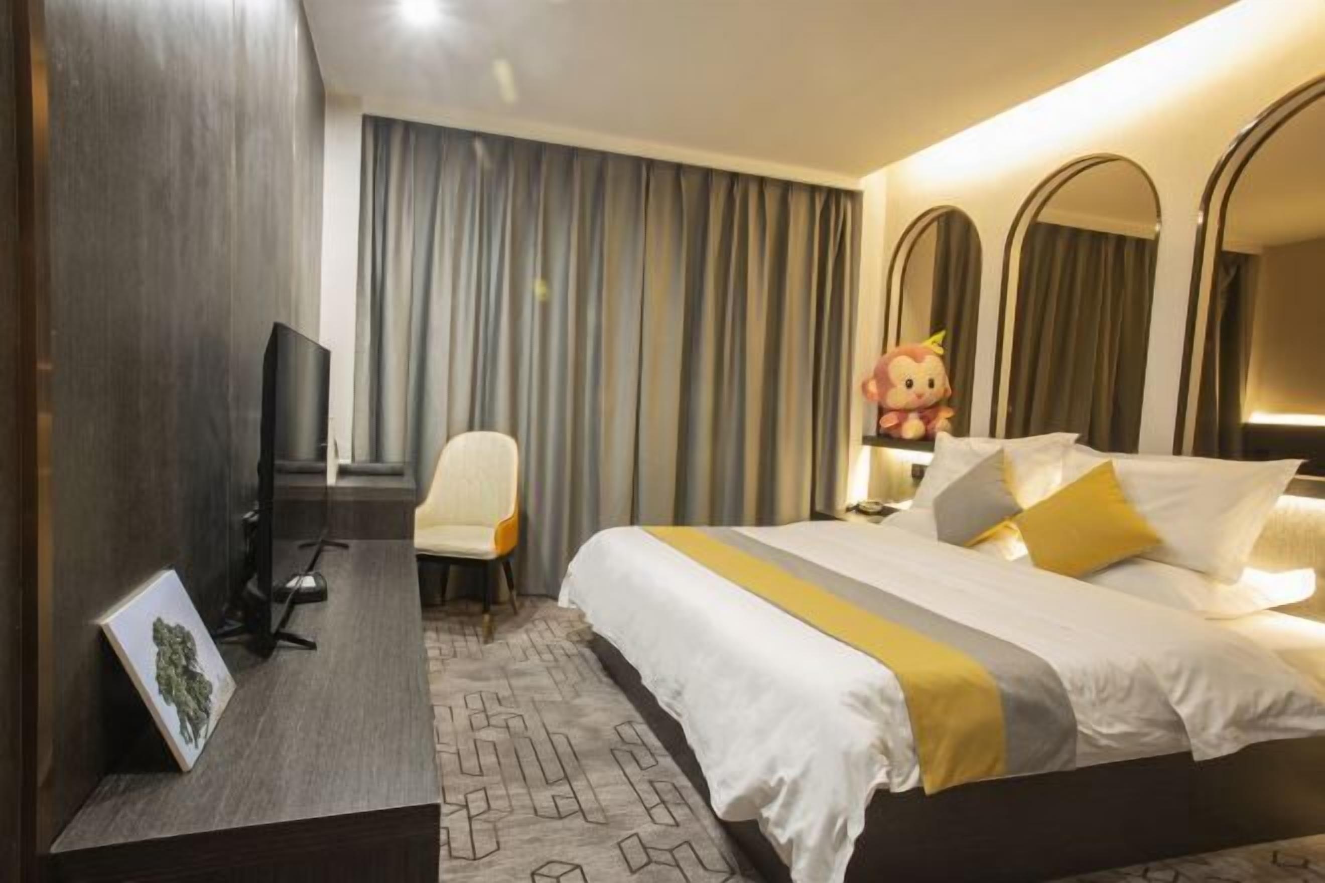 Una habitación de hotel con una cama, un escritorio, una silla, un televisor y un espejo grande.