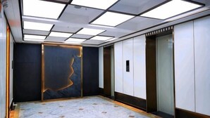 A modern elevator with a marble floor and a wall with a geometric light fixture.