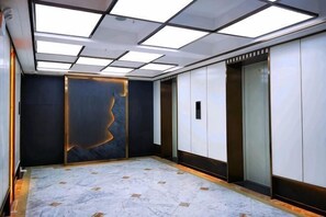 A modern elevator with a marble floor and a wall with a geometric light fixture. - Dongchuan Tongdu Hotel (Kunming)