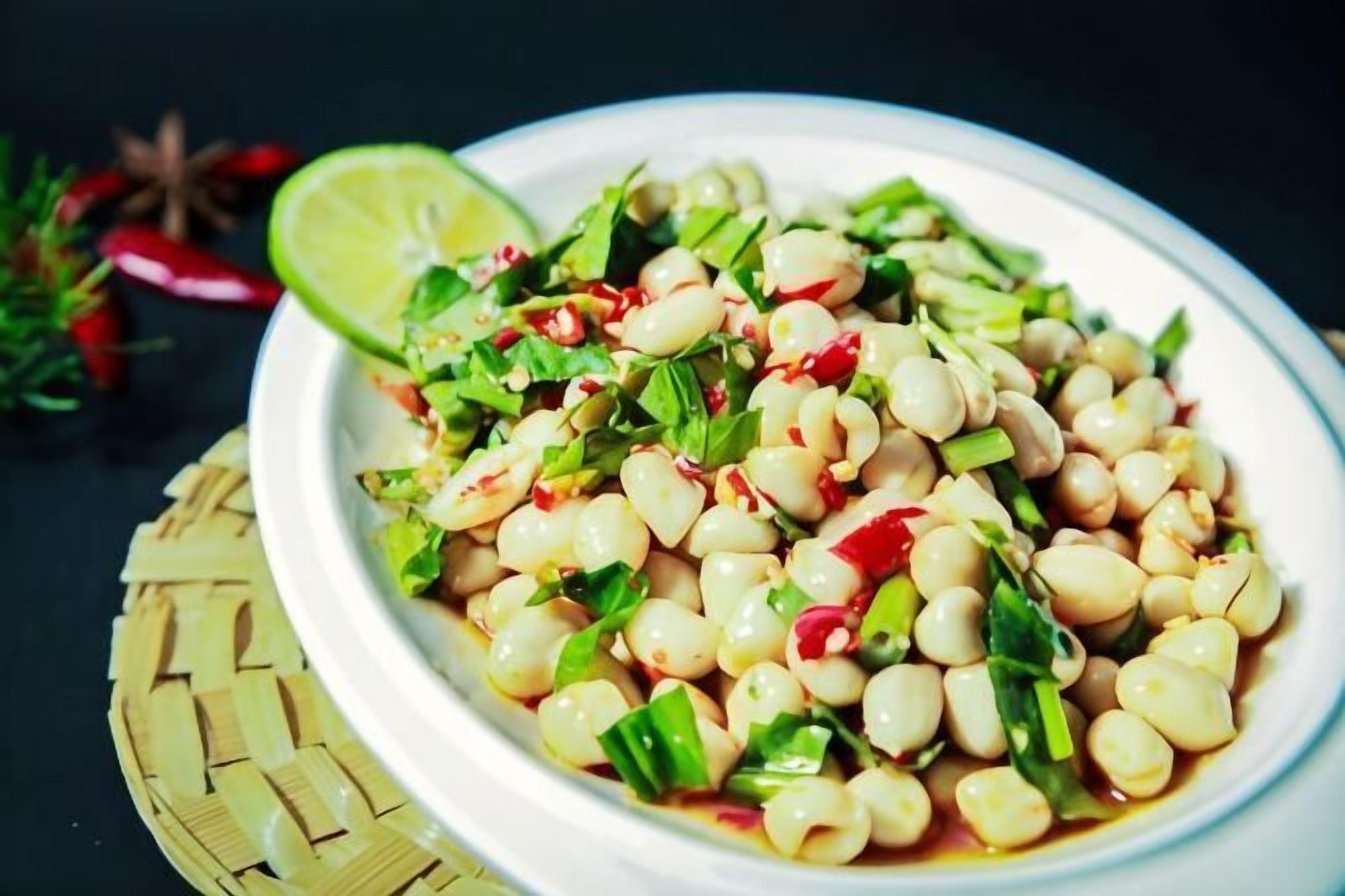 A bowl of bean salad with lime and green onions.