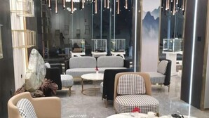A modern lounge area with checkered sofas, round tables, and a large mirror reflecting the space.