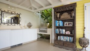 A kitchen with white cabinets, a built-in stove, and a wooden bookshelf filled with books and decorative items.