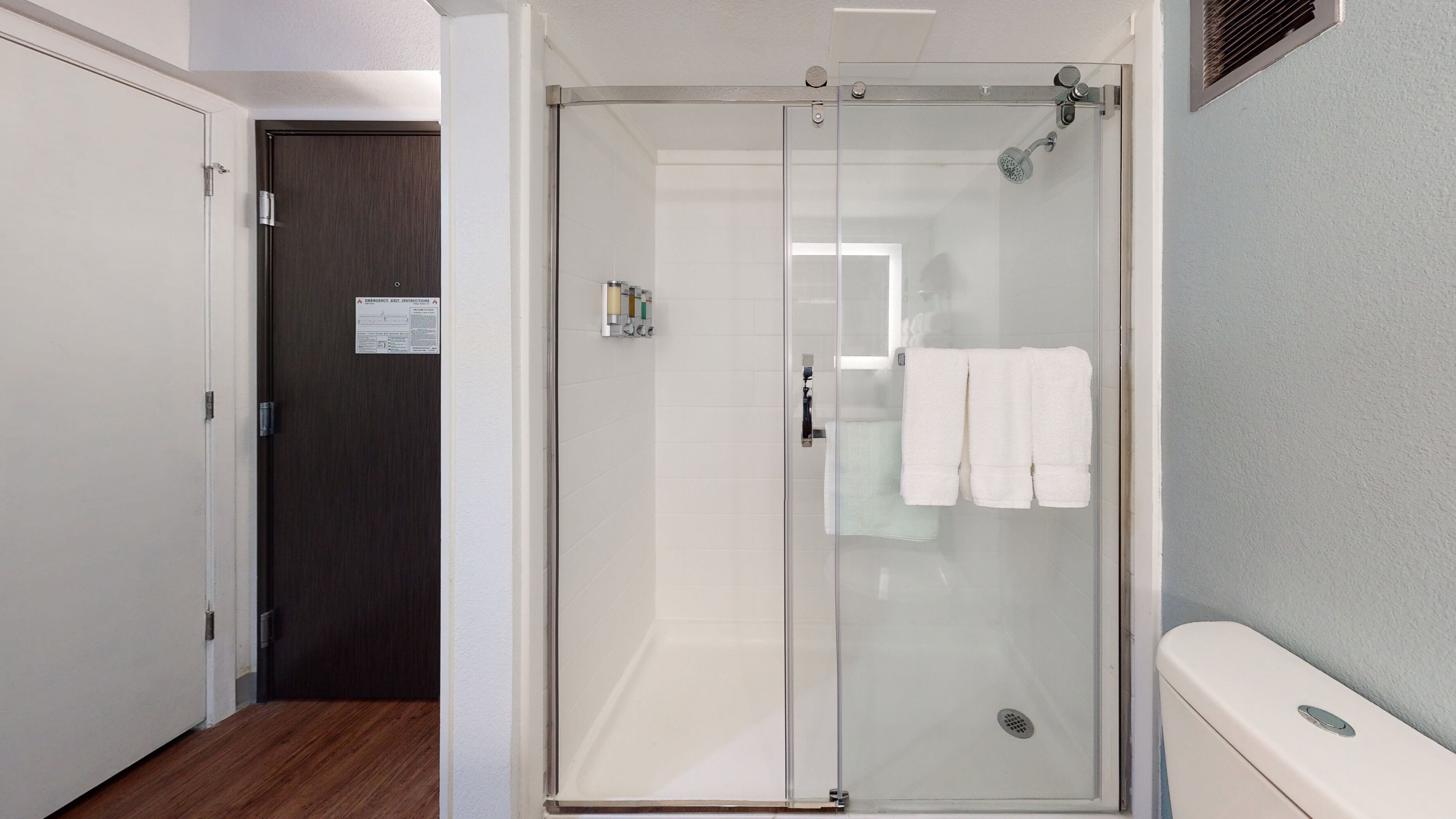 A modern bathroom with a glass-enclosed shower, a toilet, and a towel rack.