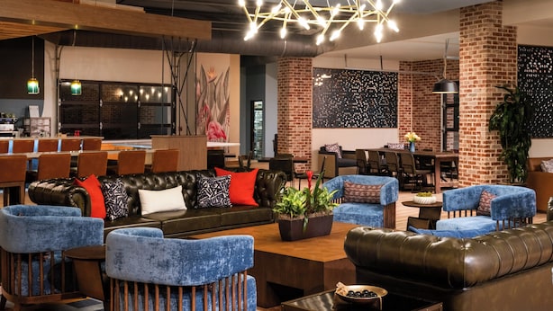 Un área de descanso moderna con sofás de cuero, sillones azules y una mesa de centro.