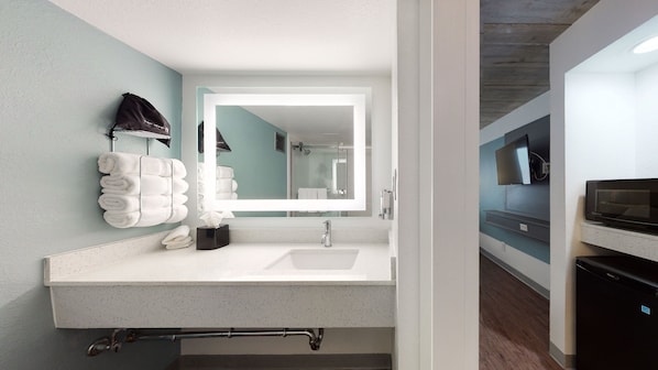 A modern bathroom with a large mirror, white sink, and towel rack.