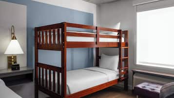 Una cama litera con estructura de madera, una mesita de noche con lámpara y una ventana con vistas.