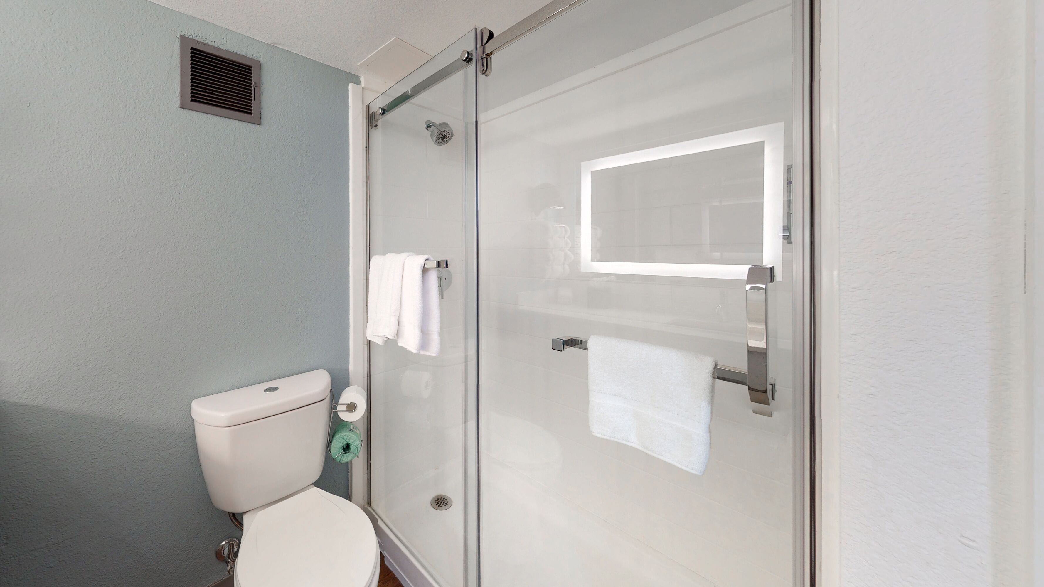 A bathroom with a toilet, a glass shower enclosure, and a towel rack.