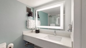 A bathroom with a white sink, a large mirror, and a towel rack with neatly folded towels.