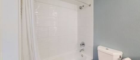 Une salle de bain avec une baignoire, des toilettes et un rideau de douche.