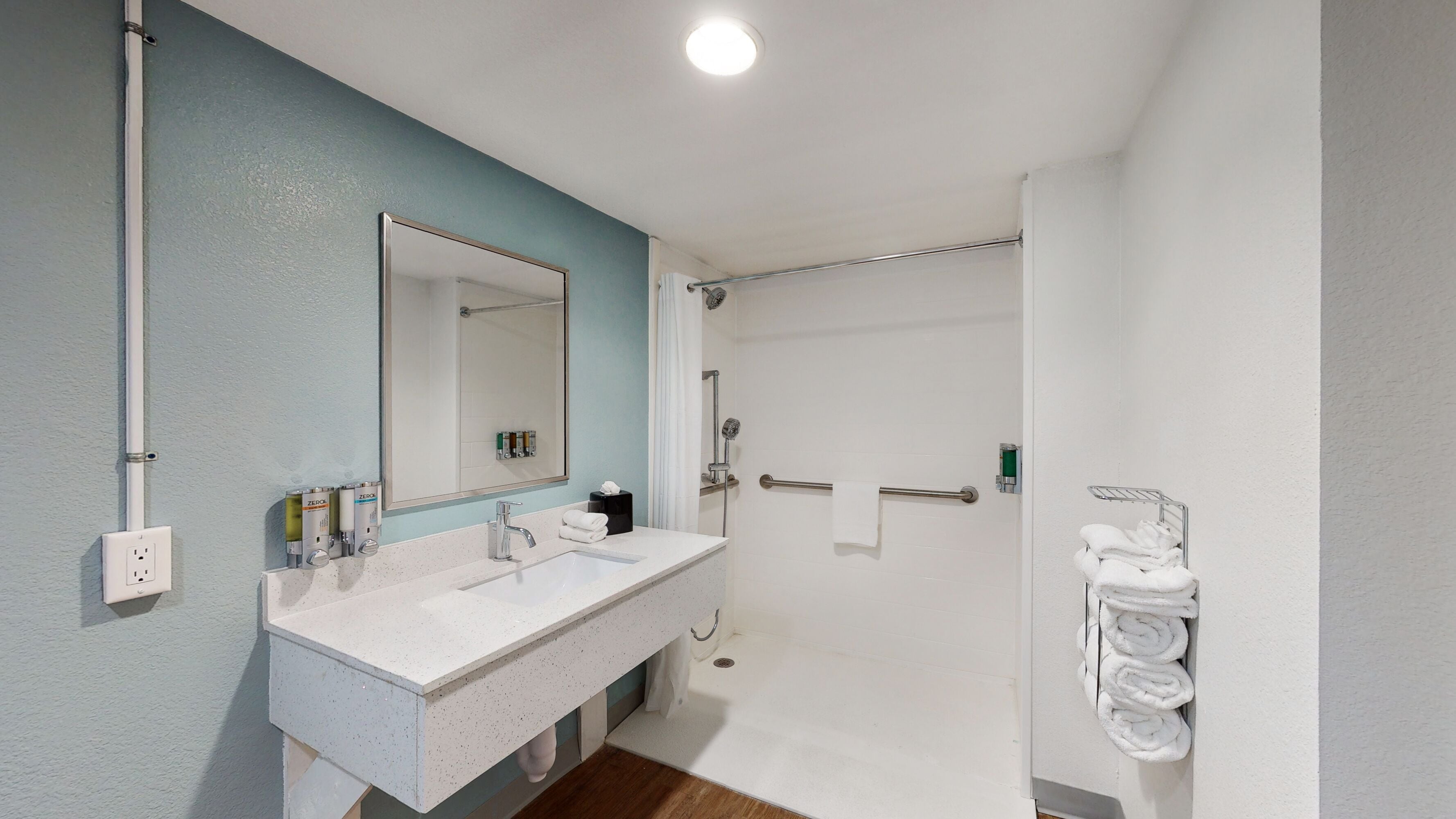 A bathroom with a white sink, mirror, and towel rack.