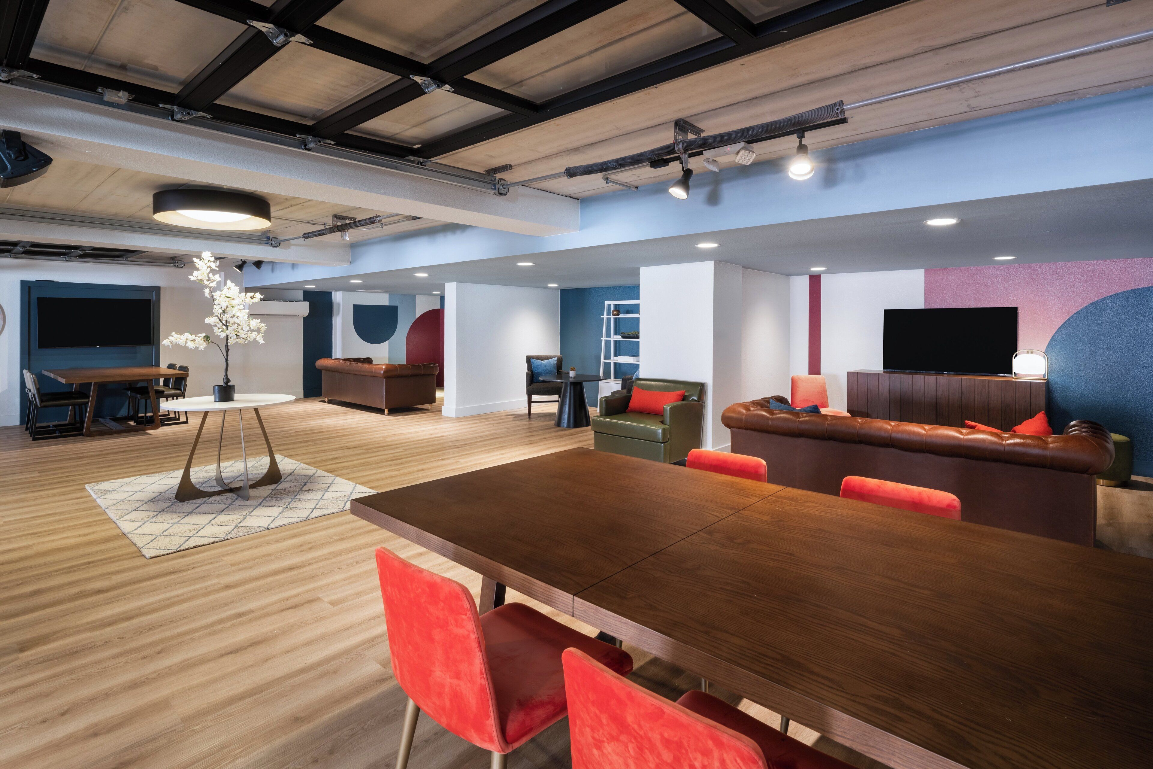 Un interior moderno con una mesa de comedor de madera, sillas rojas, un sofá y un televisor.