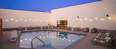 Ein Swimmingpool mit Liegestühlen und Lichterkette.