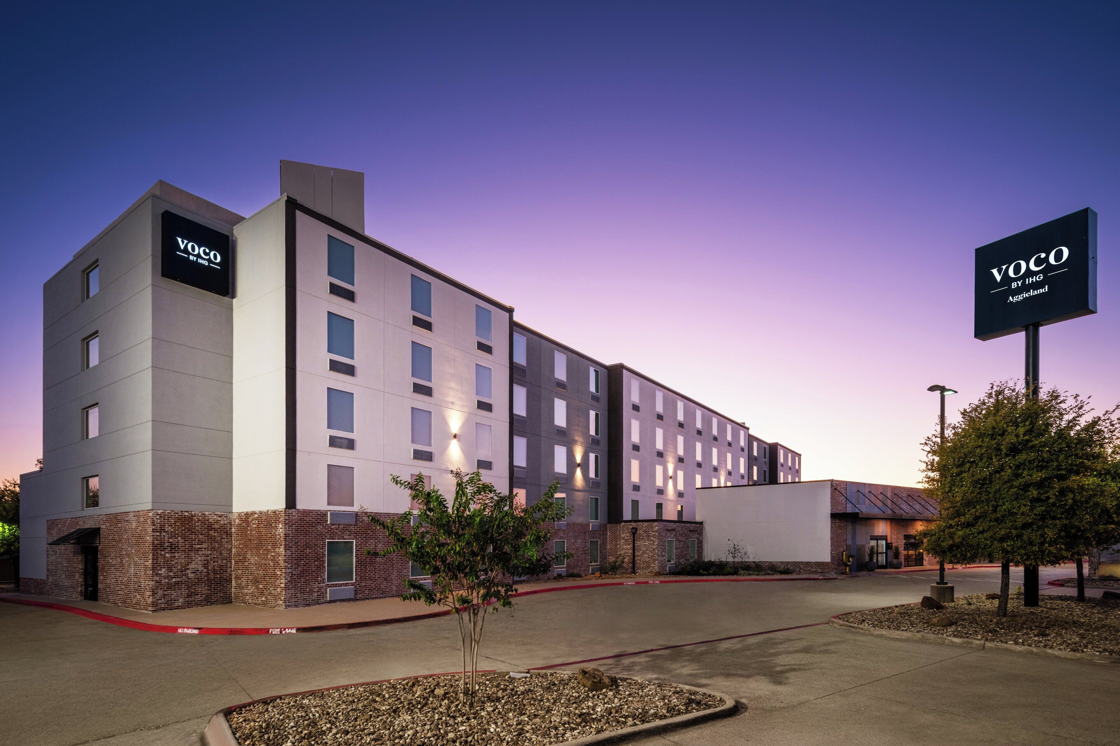 A modern hotel building with multiple floors, a brick facade, and signage indicating it is a Voco by IHG property.