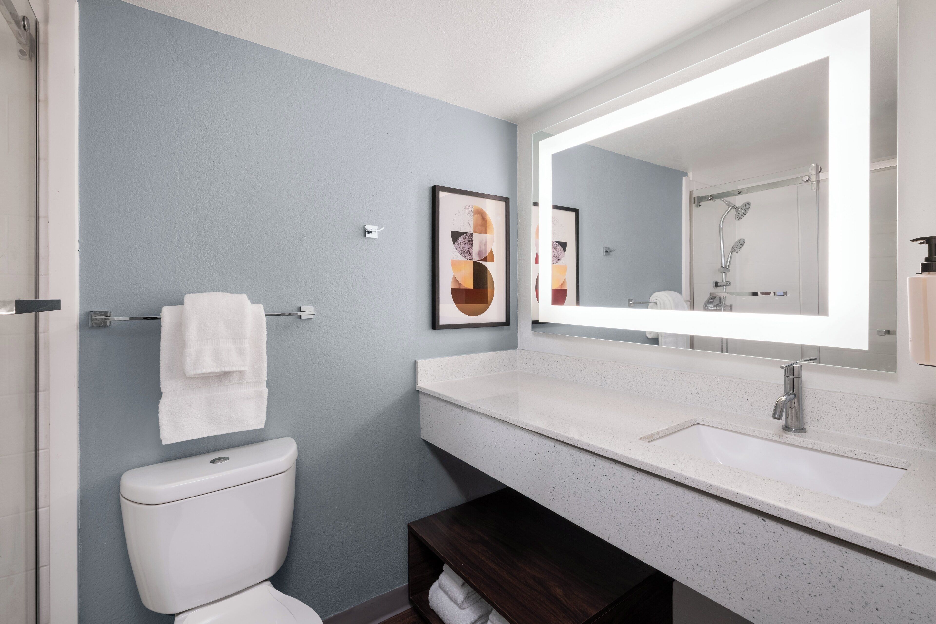 Un baño moderno con un lavabo blanco, un espejo grande y un inodoro.