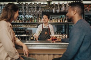 A bar setting with a bartender, a customer, and a server. - voco College Station Aggieland by IHG (College Station)