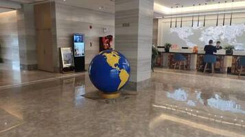 Een hal met een grote wereldbol, een receptiebalie en een wereldkaart aan de muur.