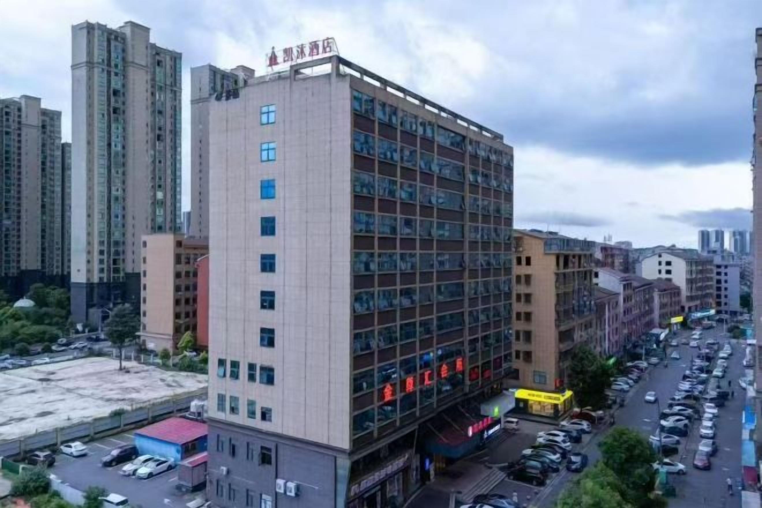 Un immeuble à plusieurs étages, doté d’une façade plate, de nombreuses fenêtres et d’un parking situé au premier plan.