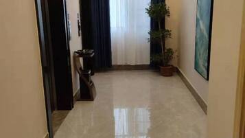 Un pasillo con una planta en maceta, un cubo de basura y un cuadro en la pared.