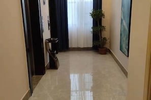 A hallway with a potted plant, a trash bin, and a painting on the wall. - Kaimu Hotel (Yiyang Ziyang District Changchun Industrial Park) (Yiyang)