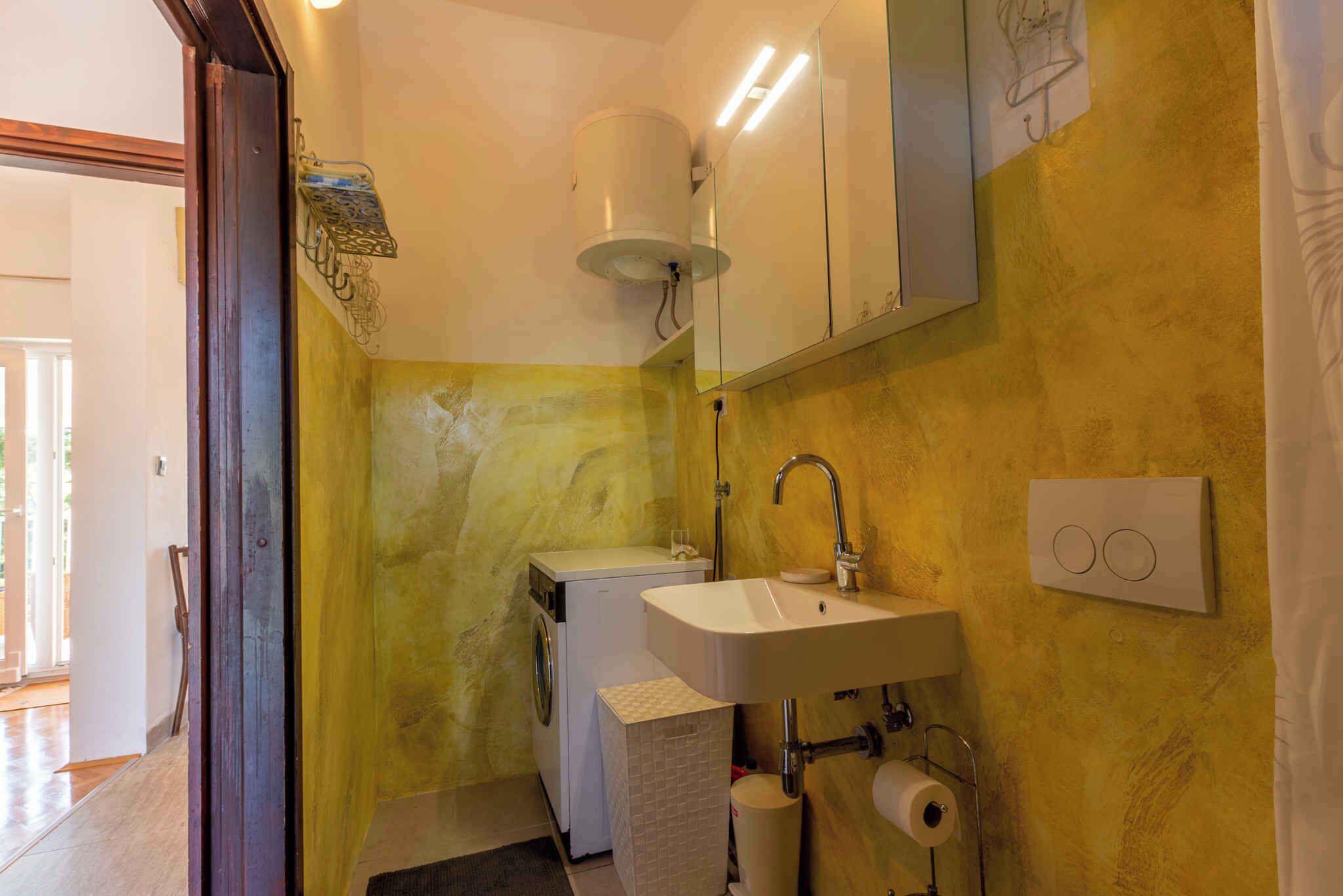 Un baño pequeño equipado con lavadora, lavamanos e inodoro.