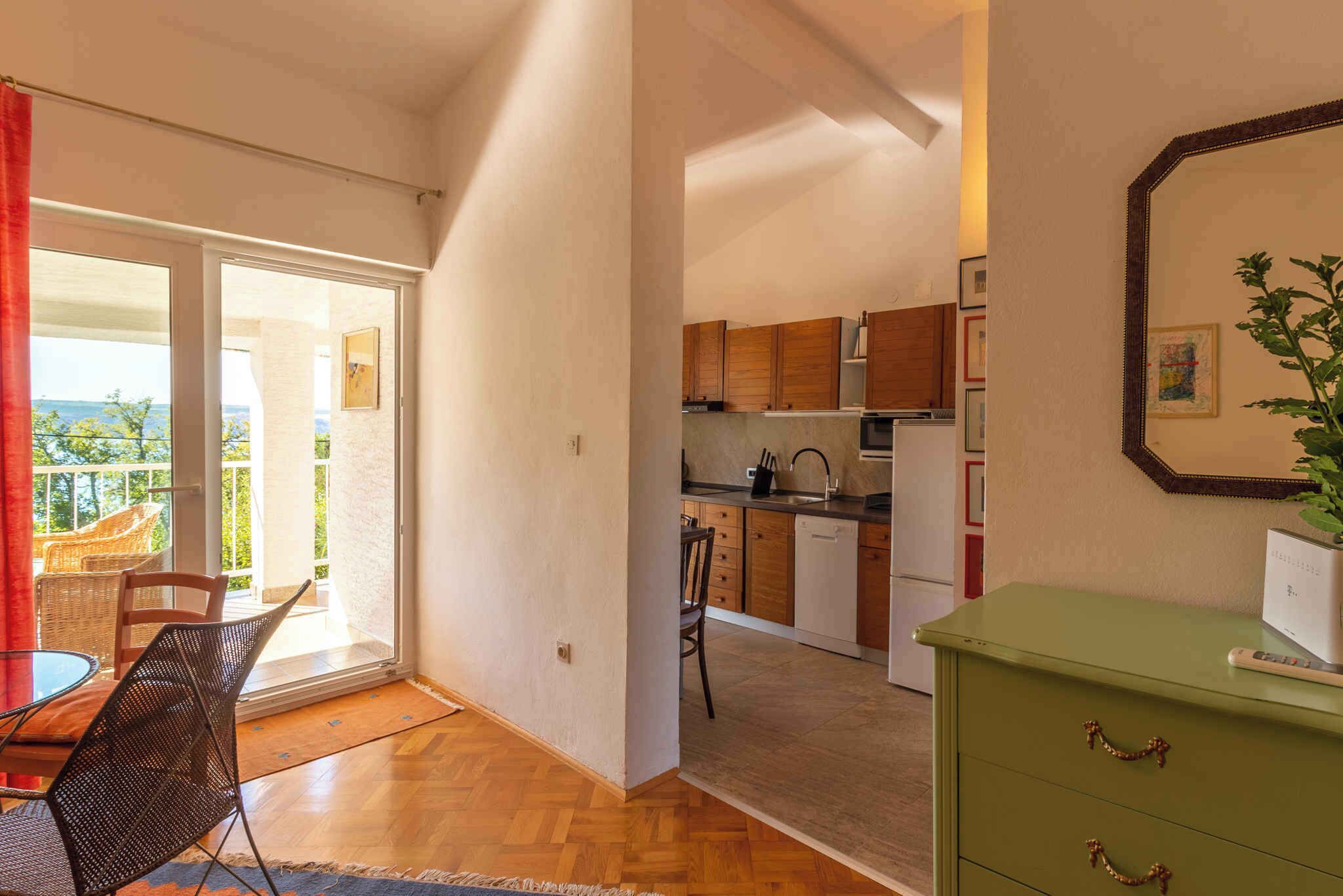 Un espace de vie compact comprenant un coin repas, une kitchenette et une porte-fenêtre coulissante donnant sur un balcon.