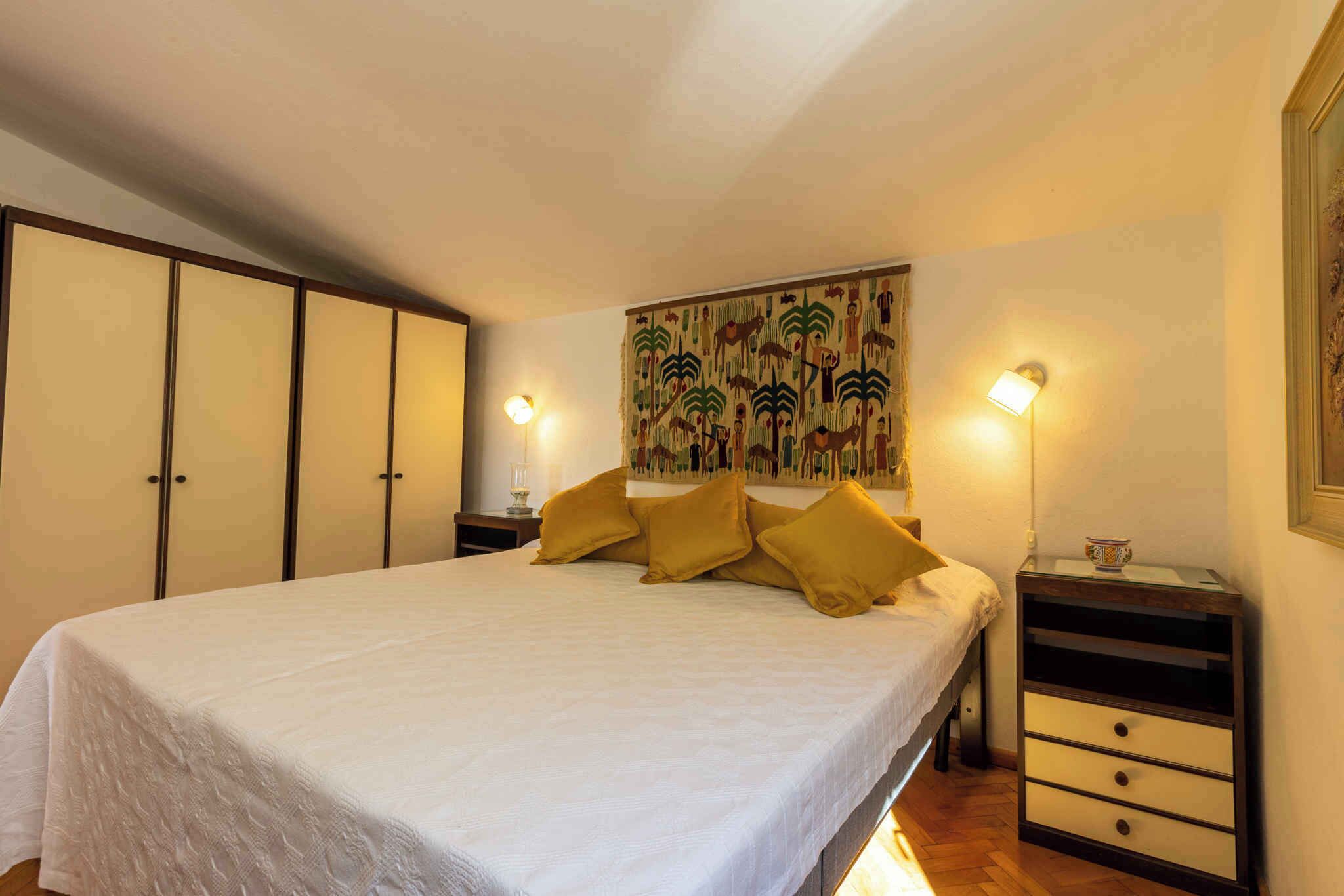 Een slaapkamer met een groot bed, een nachtkastje, een wandplank en een decoratieve wandversiering.