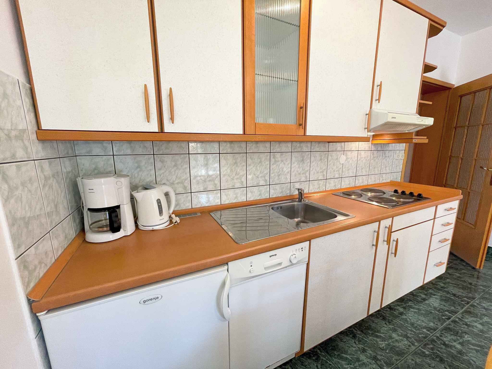 A kitchen with white cabinets, a sink, a stove, a coffee maker, and a dishwasher.