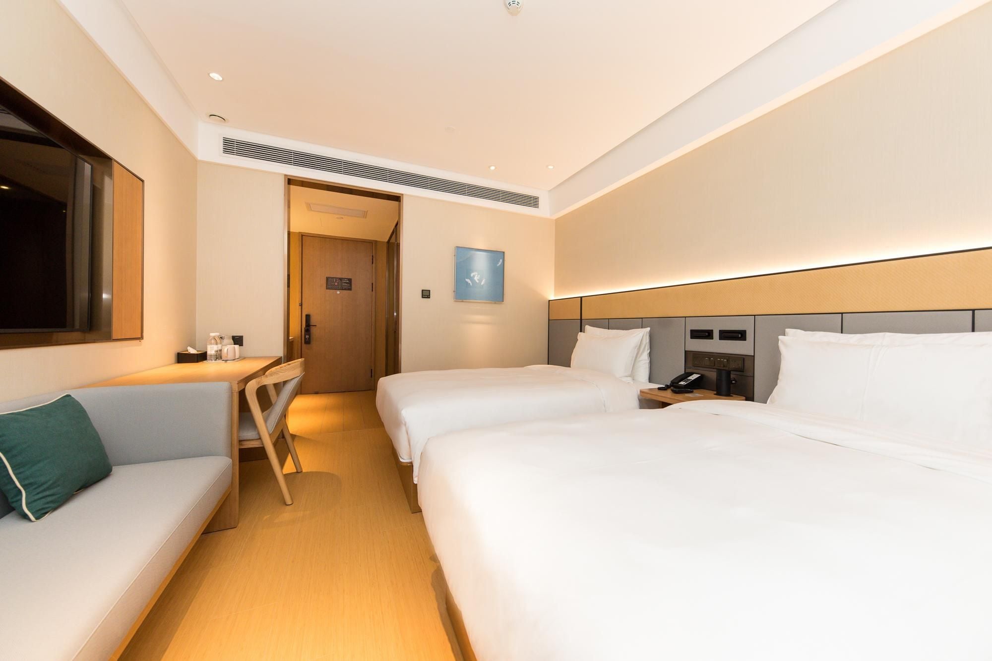 Habitación de hotel con dos camas, un escritorio, una silla, un televisor y una mesita de noche con un teléfono.
