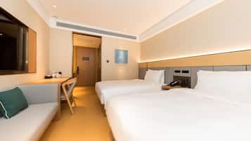 Habitación de hotel con dos camas, un escritorio, una silla, un televisor y una mesita de noche con un teléfono.
