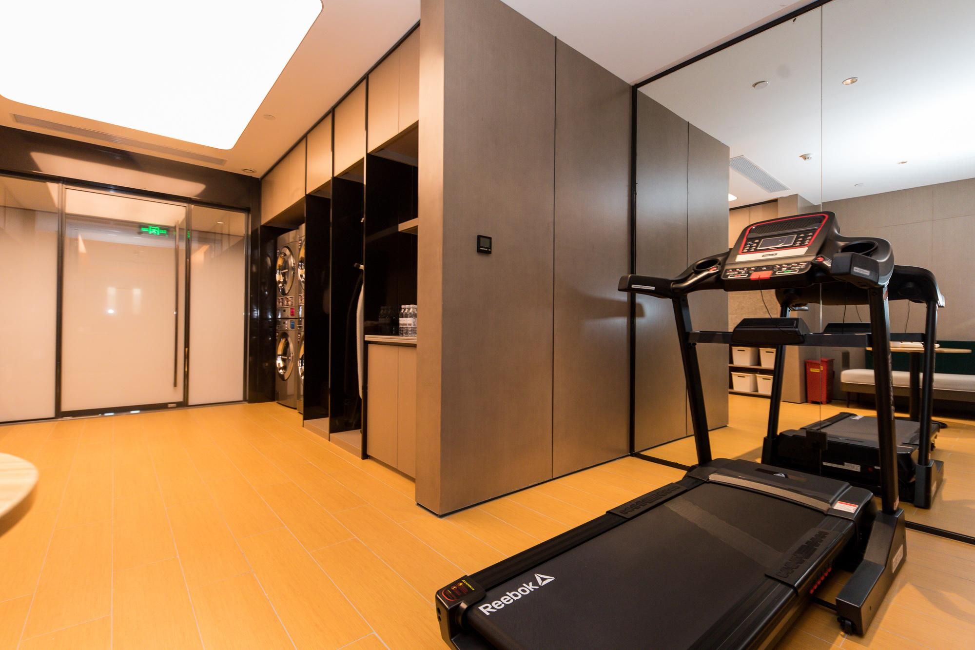 Un gimnasio moderno con una cinta de correr, una bicicleta estática y una máquina de ejercicio de pared.