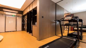 Un gimnasio moderno con una cinta de correr, una bicicleta estática y una máquina de ejercicio de pared.