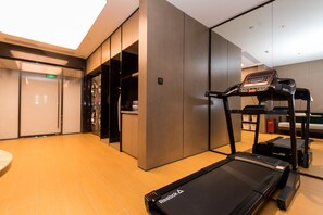 A modern hotel room with a treadmill, a small table, and a bench. - Ji Hotel (Tianjin)