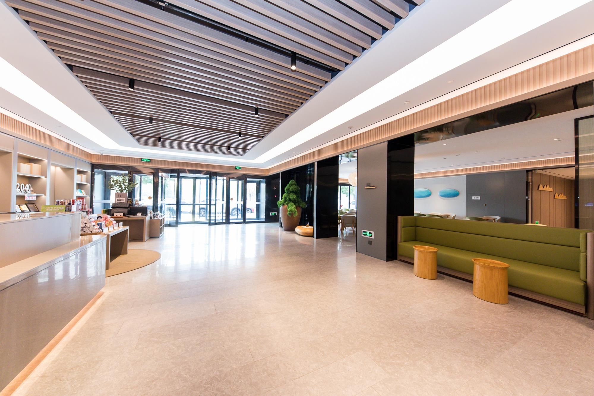 Un hall d’hôtel moderne avec un comptoir d’accueil, un espace salon et une grande fenêtre.