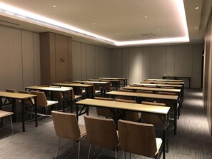 A conference room with multiple tables and chairs, equipped with ceiling lights and a carpeted floor. - Ji Hotel (Tianjin)